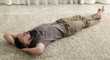 Man ligger på hemstädad matta